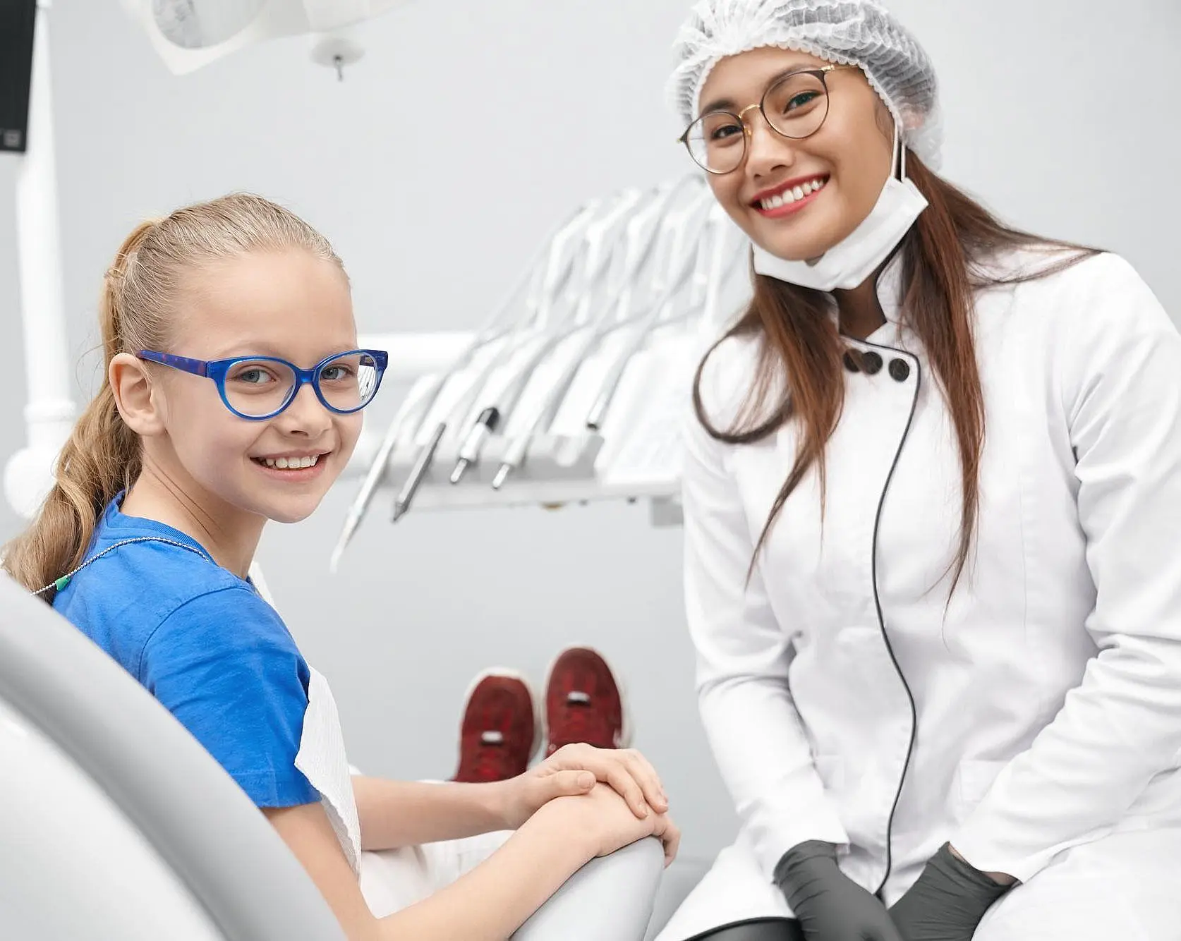 a young girl with blue glasses smiles from the dental chair at Paige Orthodontics in Kingwood TX