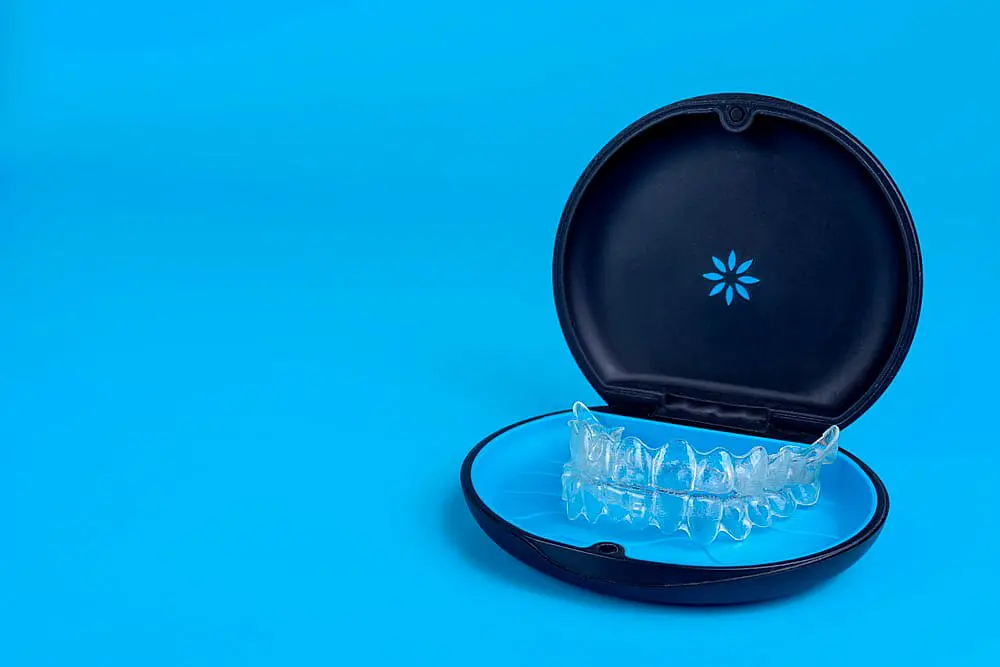 Against a serene blue background, Invisalign clear dental aligners rest elegantly in an open black case in Kingwood TX.