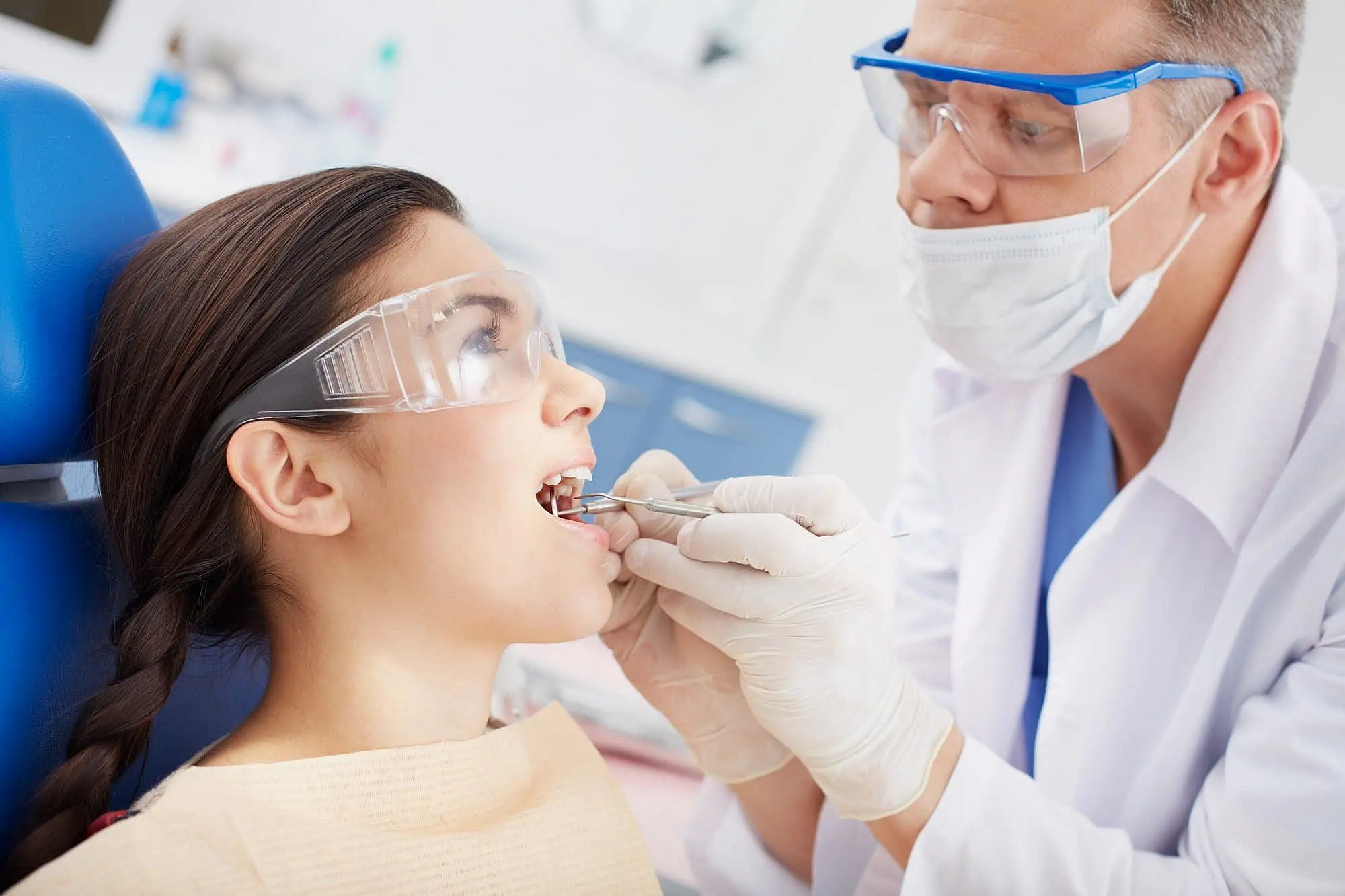 a dentist examines a patient's teeth with dental tools while the patient sits in a chair at Paige Orthodontics in Kingwood, TX