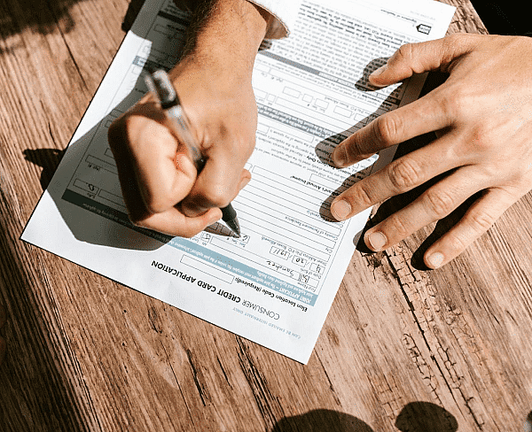 A person fills out a Invisalign Insurance application form on a wooden table at Paige Orthodontics in Kingwood, TX.