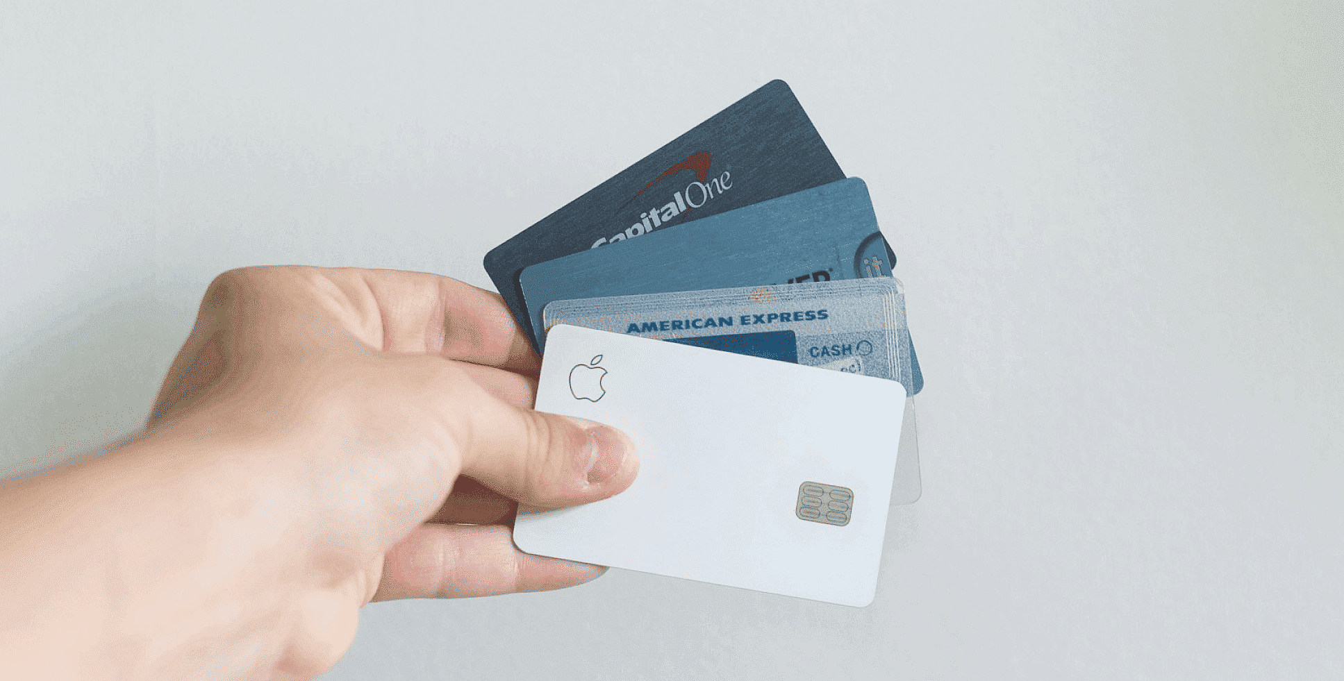 A hand holds several credit cards, including Apple Card, Capital One, and American Express, fanned out for Invisalign Payment plan at Paige Orthodontics in Kingwood, TX.
