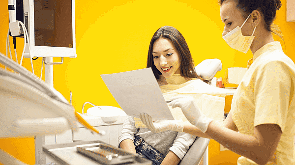 A dental shows a female patient a dental insurance document the patient sits in a dental chair at Paige Orthodontics in Kingwood, TX