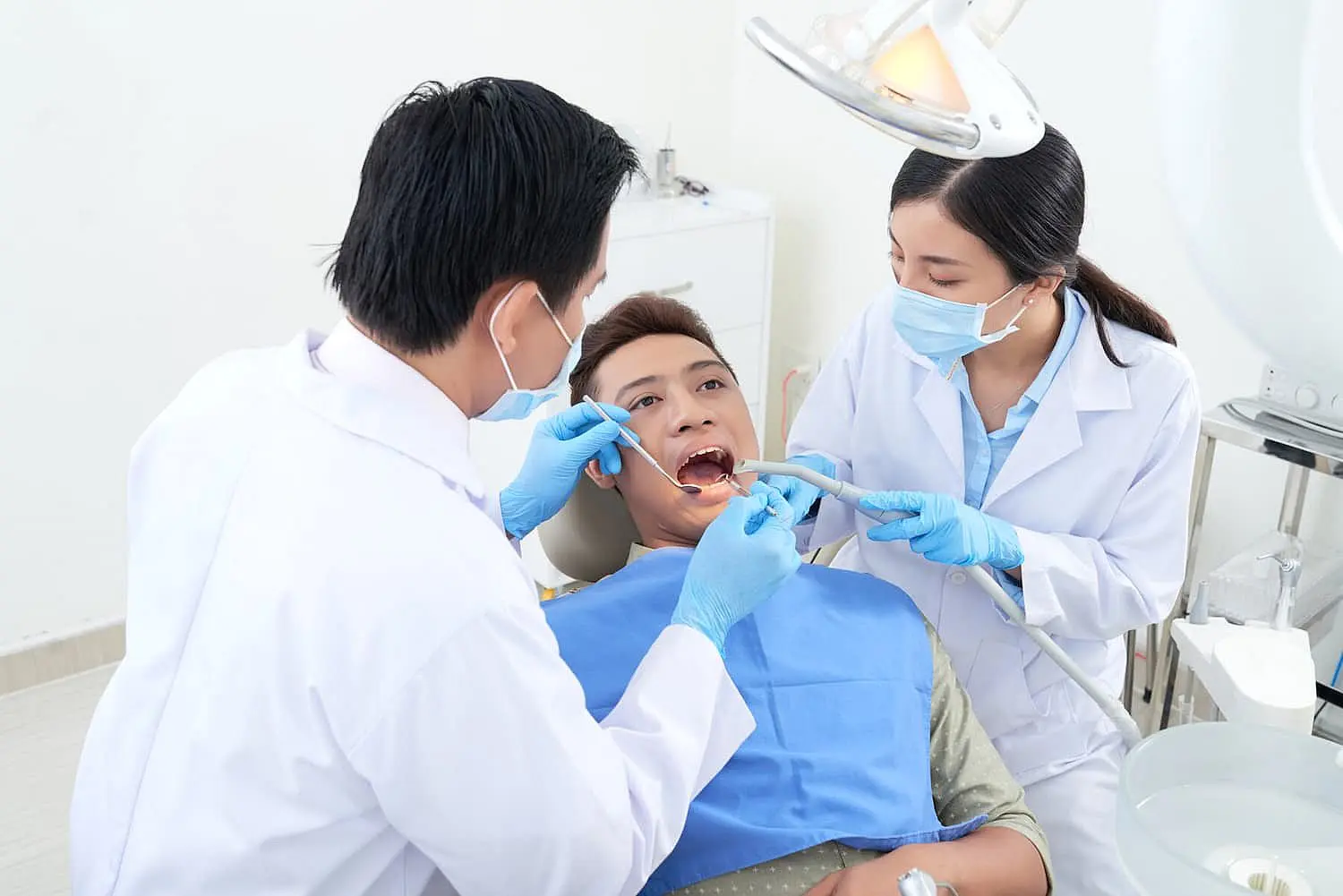 A dentist and dental assistant perform a tongue check-up on a patient in a clinic at Paige Orthodontics in kingwood, TX