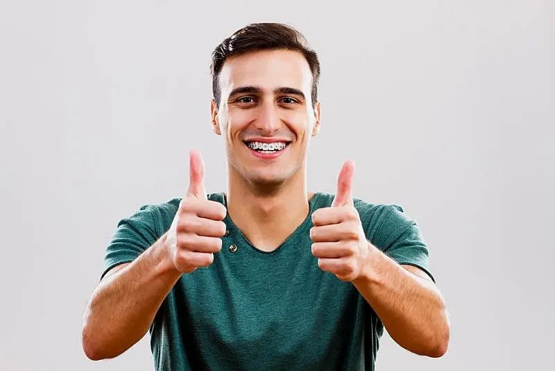 A person with metal braces smiles at the camera for recommended choice Paige Orthodontics in Kingwood, TX for solution metal braces