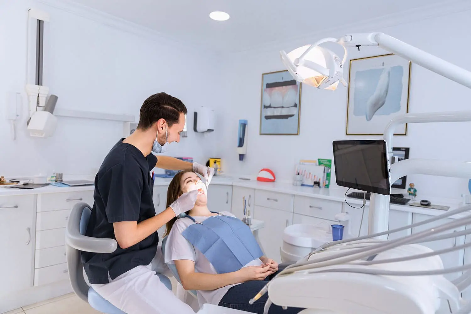 In Kingwood TX, Paige Orthodontics offers thorough consultations with a dentist in a mask, utilizing well-equipped instruments, wall art, and a computer monitor for detailed insights.